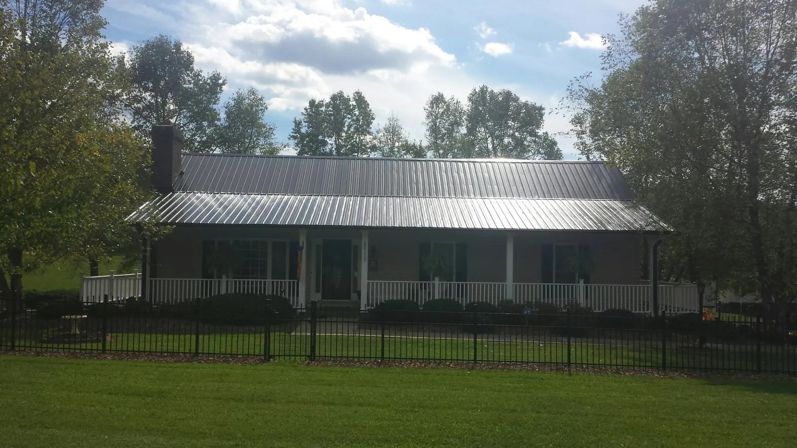 Gray metal roof on a brick ranch with a full width front porch — Gutter Guard Installation work by our crew in Snyder