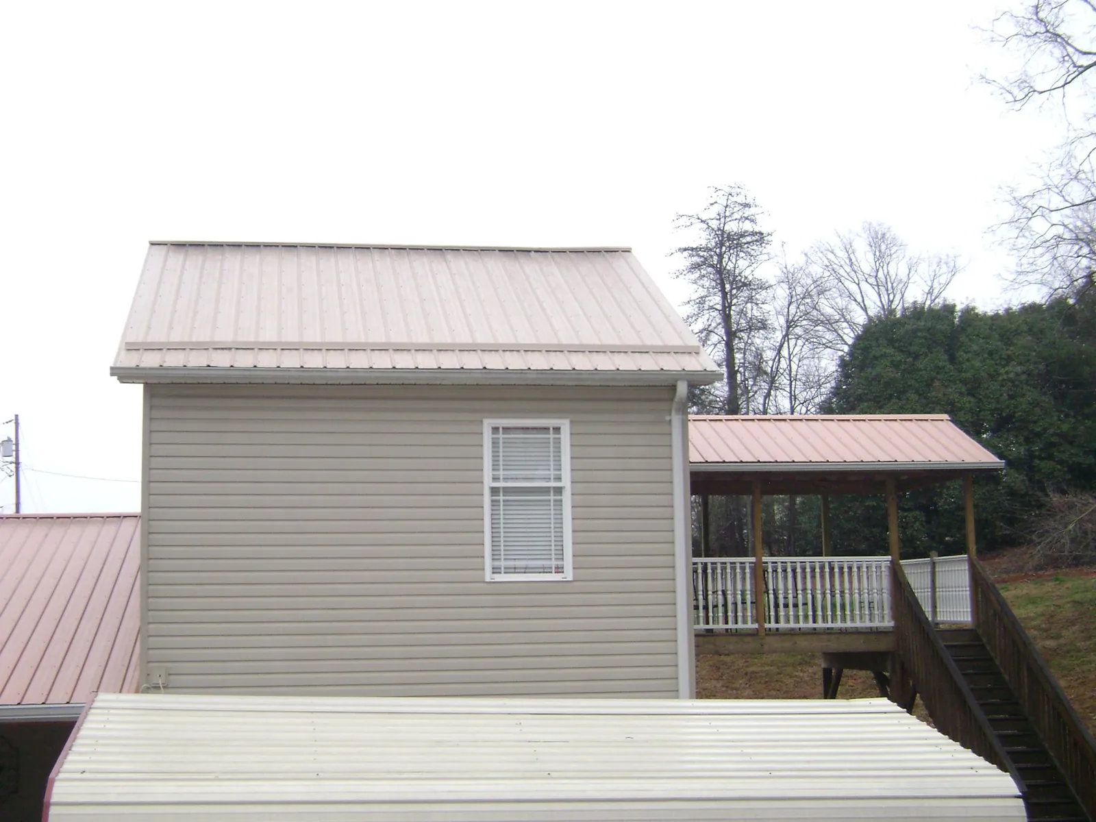 Tan metal roofs on a two story addition and attached porch, from a Roof Replacement job in Snyder
