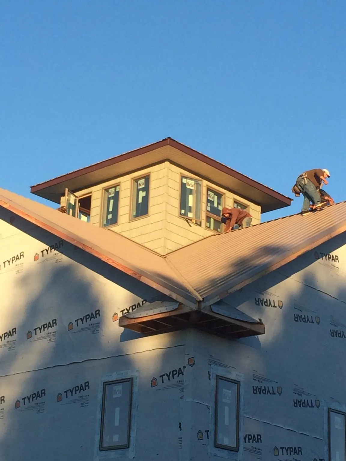 Roofers working around a rooftop cupola on a new metal roof at sunset — Roof Waterproofing in Snyder by Roofing Brothers